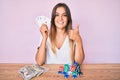 Beautiful caucasian woman playing poker holding cards smiling happy and positive, thumb up doing excellent and approval sign