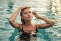 Beautiful caucasian woman relaxing in swimming pool, looking at the camera. Sunny summer day Royalty Free Stock Photo
