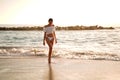 Beautiful caucasian woman on a relaxing walk on empty beach at sunset sea shore Royalty Free Stock Photo