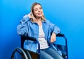 Beautiful caucasian woman sitting on wheelchair smiling doing phone gesture with hand and fingers like talking on the telephone Royalty Free Stock Photo