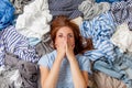 Beautiful caucasian woman smiling and lying down with clutter clothes on the floor.