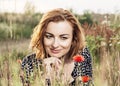 Beautiful caucasian woman is smiling and posing in poppy flowers Royalty Free Stock Photo