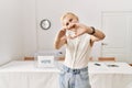 Beautiful caucasian woman standing by voting ballot at election room smiling in love showing heart symbol and shape with hands