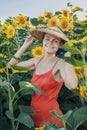 Beautiful Caucasian woman in sunflowers, portrait of a woman wearing a Vietnamese hat walking through a blooming field Royalty Free Stock Photo