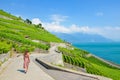 Beautiful Caucasian woman tourist walking on scenic path along terraced vineyards on slopes by Geneva Lake, Switzerland. Lavaux