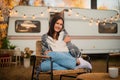 Beautiful caucasian woman travels in a motorhome. A girl wrapped in a plaid sits in a wicker chair near the camper.