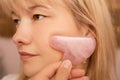 Beautiful caucasian woman using gua sha stone to massage her face in SPA salon. Beauty tools equipment for anti aging beauty Royalty Free Stock Photo