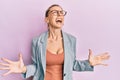 Beautiful caucasian woman wearing business jacket and glasses crazy and mad shouting and yelling with aggressive expression and Royalty Free Stock Photo