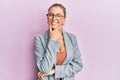 Beautiful caucasian woman wearing business jacket and glasses looking confident at the camera smiling with crossed arms and hand Royalty Free Stock Photo