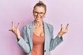 Beautiful caucasian woman wearing business jacket and glasses shouting with crazy expression doing rock symbol with hands up Royalty Free Stock Photo
