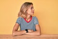 Beautiful caucasian woman wearing casual clothes sitting on the table looking to side, relax profile pose with natural face with Royalty Free Stock Photo