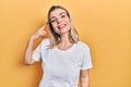 Beautiful caucasian woman wearing casual white t shirt smiling doing phone gesture with hand and fingers like talking on the Royalty Free Stock Photo