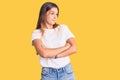 Beautiful caucasian woman wearing casual white tshirt looking to the side with arms crossed convinced and confident Royalty Free Stock Photo