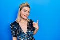 Beautiful caucasian woman wearing princess crown smiling with happy face looking and pointing to the side with thumb up Royalty Free Stock Photo