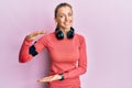 Beautiful caucasian woman wearing sportswear and arm band gesturing with hands showing big and large size sign, measure symbol Royalty Free Stock Photo