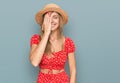 Beautiful caucasian woman wearing summer hat covering one eye with hand, confident smile on face and surprise emotion Royalty Free Stock Photo