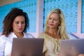 Beautiful caucasian woman and attractive afro latin mixed girl working online together with laptop computer outdoors as digital no Royalty Free Stock Photo