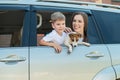 Beautiful caucasian woman travels with a child and a dog. Mom and son leaned out of the car window in an embrace with a Royalty Free Stock Photo