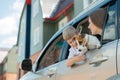 Beautiful caucasian woman travels with a child and a dog. Mom and son leaned out of the car window in an embrace with a Royalty Free Stock Photo