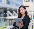 beautiful caucasian working woman in black suit standing, working with tablet outside building in city. businesswoman smile and Royalty Free Stock Photo