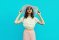 Beautiful caucasian young woman model posing wearing white summer straw hat on blue studio background Royalty Free Stock Photo