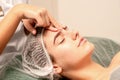 Beautiful caucasian young woman receiving a facial massage with closed eyes in spa salon, close up. Relaxing treatment Royalty Free Stock Photo
