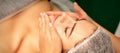 Beautiful caucasian young woman receiving a facial massage with closed eyes in spa salon, close up. Relaxing treatment Royalty Free Stock Photo