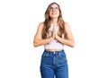 Beautiful caucasian young woman wearing casual clothes and glasses begging and praying with hands together with hope expression on Royalty Free Stock Photo