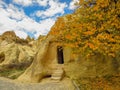 Beautiful cave house with vibrant flowers under a cloudy blue sky in Cappadocia, Turkey