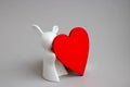 Beautiful ceramic rabbit on white background. statuette of a white rabbit with a red heart.Easter decor