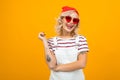 Beautiful charming blond girl with tattoos on the arms, wearing a winter red hat, striped T-shirt and sunglasses on a Royalty Free Stock Photo