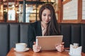 Beautiful charming brunette smiling Asian girl with tablet at table in cafe, student, freelancer or young manager Royalty Free Stock Photo