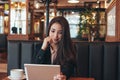 Beautiful charming brunette smiling asian girl with tablet at table in cafe, student, freelancer or young manager Royalty Free Stock Photo