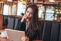 Beautiful charming brunette worried asian girl with tablet at table in cafe, student, freelancer or young manager Royalty Free Stock Photo