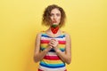 Playful girl in striped dress holding berry lollipop.