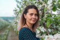 A beautiful and charming girl stands near a blossoming tree. Beautiful girl face close-up.