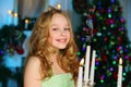 Beautiful charming pretty blond child-girl on the background of a New Year tree