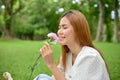 Beautiful Asian female in the garden, admiring pink flower in her hand, smelling the flower Royalty Free Stock Photo