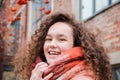 Beautiful charming young teen girl with curly loose hair in a warm scarf looks at the camera and smiles, portrait of a girl Royalty Free Stock Photo