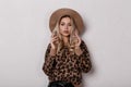 Beautiful charming young woman in a trendy stylish leopard sweater in trendy black leather pants and a beige hat posing indoors Royalty Free Stock Photo