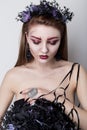 Beautiful cheeky girl in the image of a vampire with bright dark makeup, black vampire bride with a bouquet and a black wreath Royalty Free Stock Photo