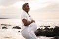 Beautiful cheerful african american pregnant woman holding her belly, smiling, looking with hope to the future. Real people Royalty Free Stock Photo