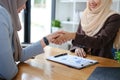 A beautiful and cheerful Asian Muslim businesswoman shaking hands with a female business partner during the meeting in Royalty Free Stock Photo