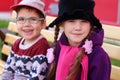 Beautiful cheerful children, boy and girl in bright clothes sitting on bench, focus on girl