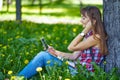 Beautiful cheerful girl with a smartphone sitting in a park on a bench on a sunny dayteenager, on-line shopping concept Royalty Free Stock Photo