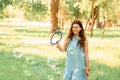 Beautiful cheerful girl stands in the park and inflates soap bubbles