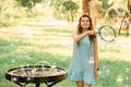 Beautiful cheerful girl stands in the park and inflates soap bubbles