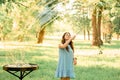 Beautiful cheerful girl stands in the park and inflates soap bubbles