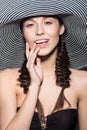 Beautiful cheerful girl in a summer beach striped hat. The beauty of the face. Royalty Free Stock Photo