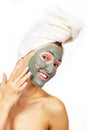 Beautiful cheerful teen girl applying facial clay mask. Beauty treatments, isolated over white Royalty Free Stock Photo